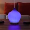 Leah diffuser by GreenAir sitting on coffee table with blue light and steam