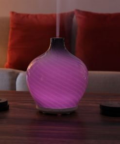 Leah diffuser by GreenAir sitting on coffee table with blue light and steam