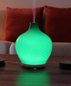 Leah diffuser by GreenAir sitting on coffee table with green light and steam