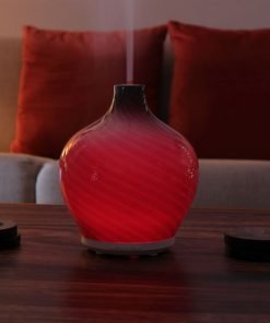 Leah diffuser by GreenAir sitting on coffee table with red light and steam