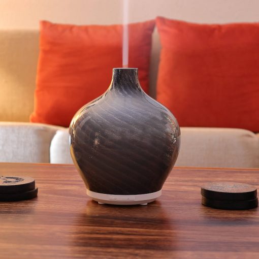 Leah diffuser by GreenAir sitting on a coffee table, light off with steam